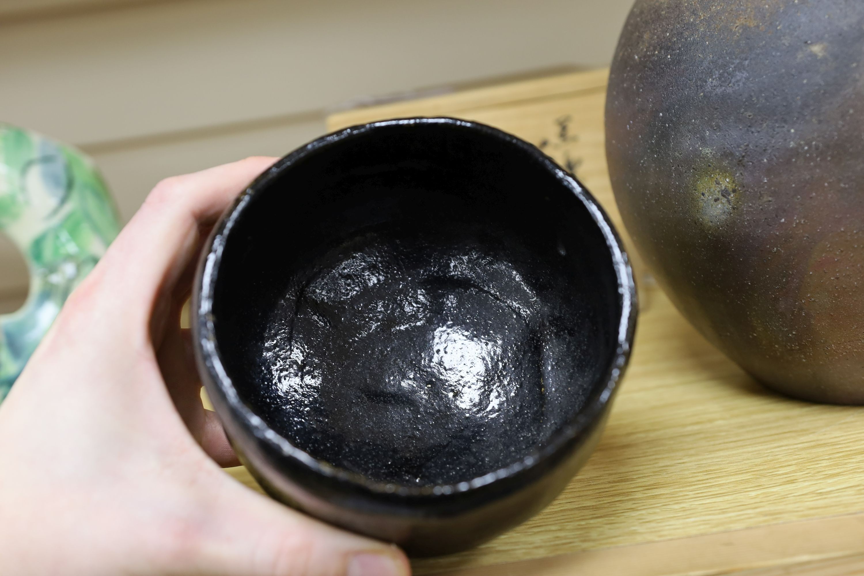 Japanese studio pottery: a boxed black glaze stoneware unomi tea bowl, with impressed mark, together with a ovoid vase, marked, 21cm tall